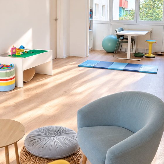 Spielbereich mit Bodenkissen, hellblauem Sessel und Spieltisch